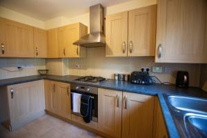 a kitchen with wooden cabinets and a stove and a sink at Picket House - Andover in Andover