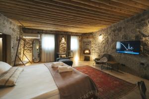 a bedroom with a large bed and a tv on a wall at Vie Cappadocia - Adults Only in Nevsehir