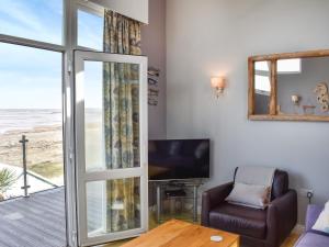 ウエストワード・ホーにあるSeapool Retreatのリビングルーム(ガラスのスライドドア、テレビ付)