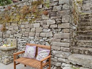 un banco con dos almohadas sentado frente a una pared de piedra en Tree Tops, en Youlgreave