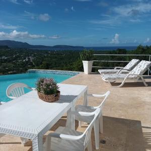 a white table and chairs next to a swimming pool at Apartamento panorámico vista al mar in Las Galeras