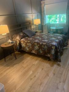 a bedroom with a bed and two tables and two lamps at Skyline Motel in Fredericton
