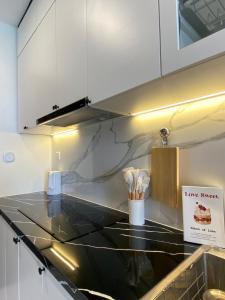 a kitchen with white cabinets and a black counter top at Căn hộ Master có sofa giường view sông Đồng Nai in Long Bình