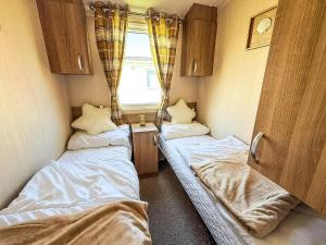 twee bedden in een kleine kamer met een raam bij Lovely 8 Berth Caravan At California Cliffs, Near Scratby Beach Ref 50046L in Great Yarmouth