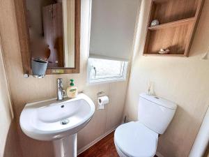 een kleine badkamer met toilet en wastafel bij Lovely 8 Berth Caravan At California Cliffs, Near Scratby Beach Ref 50046L in Great Yarmouth