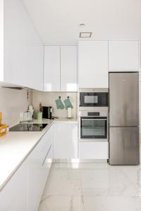 Una cocina con gabinetes blancos y electrodomésticos de acero inoxidable. en Villa Atlantica One luxury and unique with ocean view, en Lourinhã