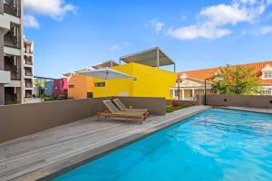 una piscina con una sedia e un edificio giallo di Casa Orillia de Mar - The Wharf 5F a Willemstad
