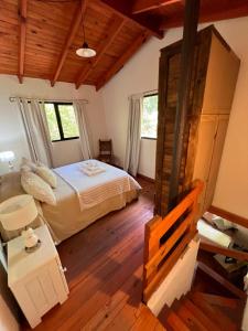 ein Schlafzimmer mit einem Bett in einem Zimmer mit Holzboden in der Unterkunft Las Camellias in La Cumbre