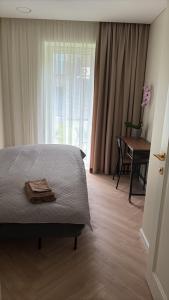 a bedroom with a bed and a table and a window at Luxury Šarli Apartment Nemirsetos parke in Palanga