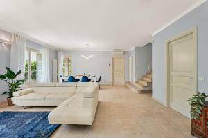 ein Wohnzimmer mit weißen Möbeln und blauen Stühlen in der Unterkunft GOLDEN LUXE - Villa Golden next Twiga Beach Club in Marina di Pietrasanta