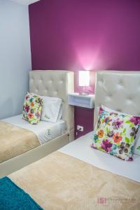 a bedroom with two beds and a purple wall at Apartamento con parqueadero, piscinas y wifi a 5 min del parque del café in Montenegro