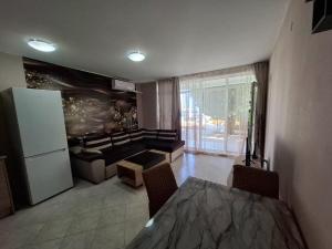 ein Wohnzimmer mit einem Tisch und einem Kühlschrank in der Unterkunft Sunset Complex Кошарица Апартамент 15 in Kosharitsa