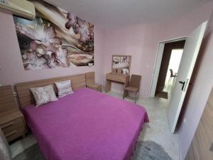 Schlafzimmer mit einem lila Bett und einem Schreibtisch in der Unterkunft Sunset Complex Кошарица Апартамент 15 in Kosharitsa + 5 Fotos