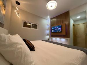 a bedroom with a bed with a tv on the wall at Santana Building in San Pedro de Macorís