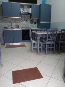 een keuken met blauwe kasten en een tafel en stoelen bij Verti House appartamento, Frignano in Frignano