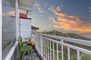 a balcony with a table and chairs with a view of the ocean at City Central Hotel l AC Rooms & Mall Road Kasauli in Kasauli
