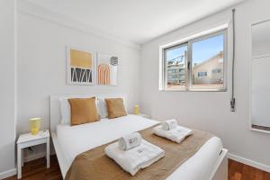 een witte slaapkamer met een bed en een raam bij GuestReady - Fantastic family home in Salgueiros in Porto