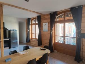 a dining room with a table and chairs and windows at Le Victoria in Briançon +5 photos
