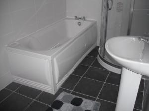 a bathroom with a tub and a sink and a toilet at The Blue House Apartments in Bushmills