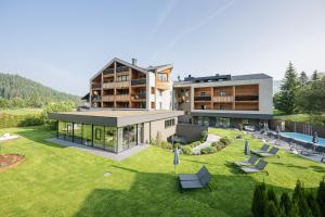 a house with a large yard with chairs and a building at Hotel Laurin in Dobbiaco