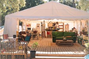 a tent with a green couch and a woman in a kitchen at Le Spot Saint-Trojan in Saint-Trojan-les-Bains