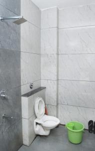 a bathroom with a toilet and a green bucket at Manibhadra home stay in Ujjain