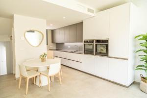 a kitchen with white cabinets and a white table and chairs at Tarifa Cozy House - Casa Verde Agua in Tarifa