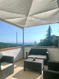 a patio with a couch and tables and a white canopy at Colibrì in Maierà