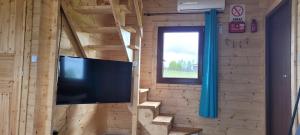 een woonkamer met een tv en een houten muur bij Domek nad jeziorem Jan, Giże in Giże