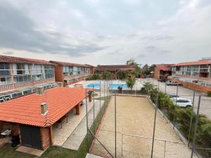 a tennis court with a fence in front of a building at Chalé Maresia Maranduba in Ubatuba