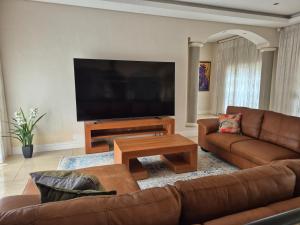 a living room with a couch and a flat screen tv at Jumanji Safaris Villa Constantia in Cape Town