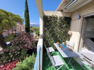 a balcony with a table and chairs and flowers at Charmant T1 climatisé avec Terrasse & Accès Piscine in Le Lavandou
