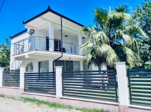 a white house with a palm tree in front of it at Residence Mary in Velipojë