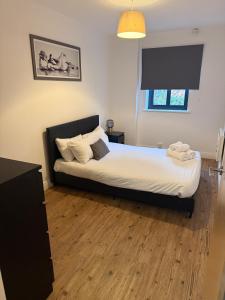una camera da letto con letto, lenzuola bianche e pavimenti in legno di Stylish 2 Bed Flat by O2 Arena Modern Comfort in Central Birmingham a Birmingham