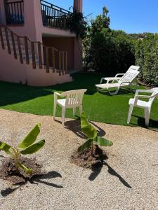 a group of white chairs sitting in a yard at Appartamento La Vela Blu in Cuile Pazzoni
