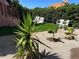 a group of white chairs and a plant in a yard at Appartamento La Vela Blu in Cuile Pazzoni