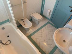 a bathroom with a toilet and a tub and a sink at Appartamento La Vela Blu in Cuile Pazzoni