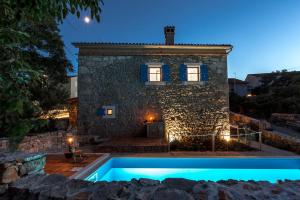 a house with a swimming pool in front of a building at Villa Marevic in Vrh