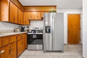 a stainless steel refrigerator in a kitchen with wooden cabinets at Rancho Alegre Country Retreat in Pueblo