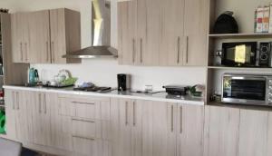 a kitchen with wooden cabinets and a microwave at Casa con piscina en Condominio Lago Rapel BLQ in El Estero