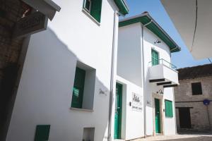 a white building with green windows and a balcony at Elite luxury Suites in Omodos