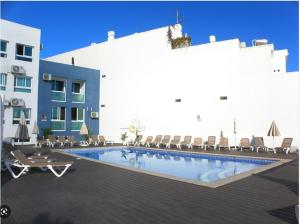 a swimming pool in front of a building with chairs at Bayview Old Town Beach Apartment in Albufeira