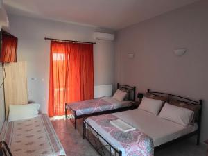 a room with two beds and a couch and a window at Kakovatos Guest Rooms in Kakovatos