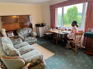a woman sitting at a table in a living room at Ashfield in Breakish