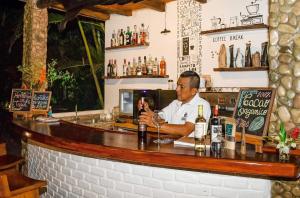 a man sitting at a bar with a bottle of wine at El Campito Lodge in Ayampe