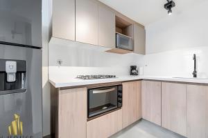 El PobladoにあるCasa Solei 12-9 - Stylish Apt with Jacuzzi & ACの木製のキャビネットとコンロ付きオーブンを備えたキッチン
