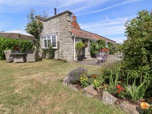 a stone house with an umbrella and a garden at Pear Tree Cottage in Mark