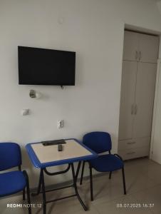 Habitación con mesa, sillas y TV de pantalla plana. en Hostel Lux, en Bitola