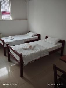 Dos camas individuales en una habitación con ventana. en Hostel Lux, en Bitola