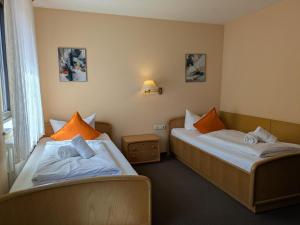 a hotel room with two beds with orange pillows at Hotel Walzwerk in Dillingen an der Saar